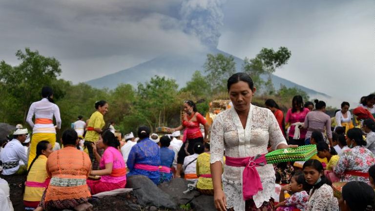 Balinese Hindus take part in a ceremony, where they pray near Mount Agung in hope of preventing a volcanic eruption, in Muntig village of the Kubu sub-district in Karangasem Regency on Indonesia's resort island of Bali on November 26, 2017. A volcano on the Indonesian tourist island of Bali sent plumes of grey smoke and steam thousands of metres into the air on November 26 for the third day in a week, triggering flight cancellations which have left thousands of tourists stranded, officials said Sunday. / AFP PHOTO / SONNY TUMBELAKA